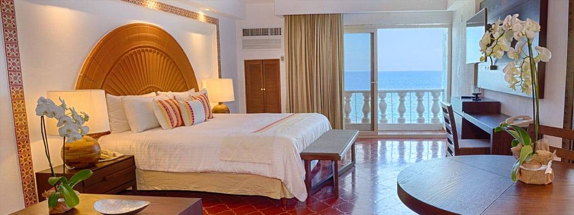 A spacious bedroom featuring a bed and a large window showcasing a stunning view of the ocean.