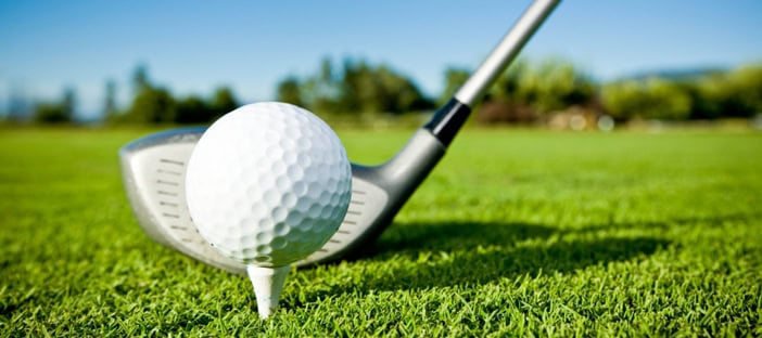 Golf ball and club on a lush green golf course.