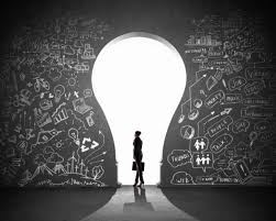 Person standing in front of a large lightbulb-shaped opening with chalkboard drawings.