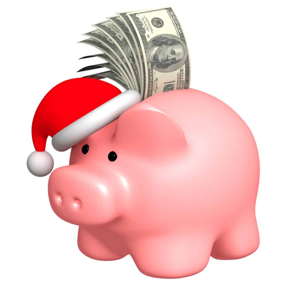 Piggy bank wearing Santa hat with dollar bills sticking out of the top.