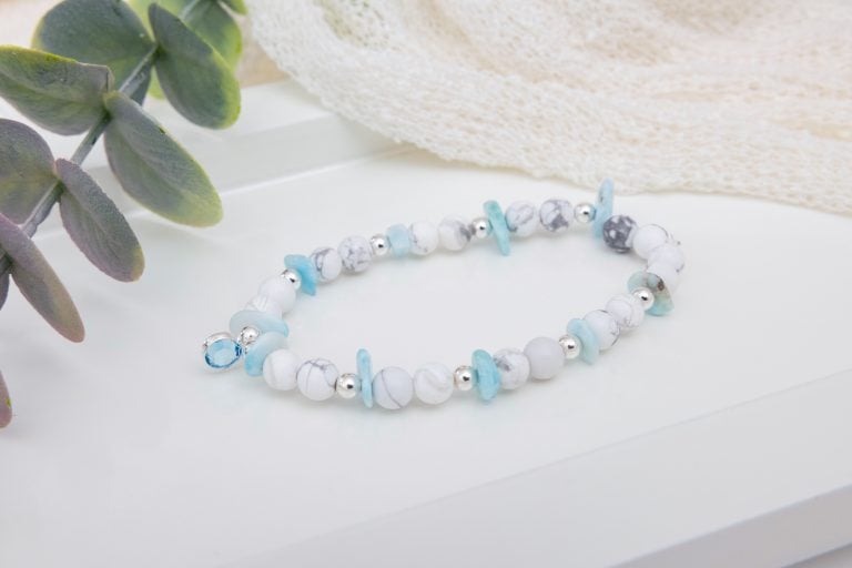 Handmade howlite and larimar chip bracelet with sterling silver beads and an aquamarine birthstone bead centerpiece on a soft, ocean-inspired background.