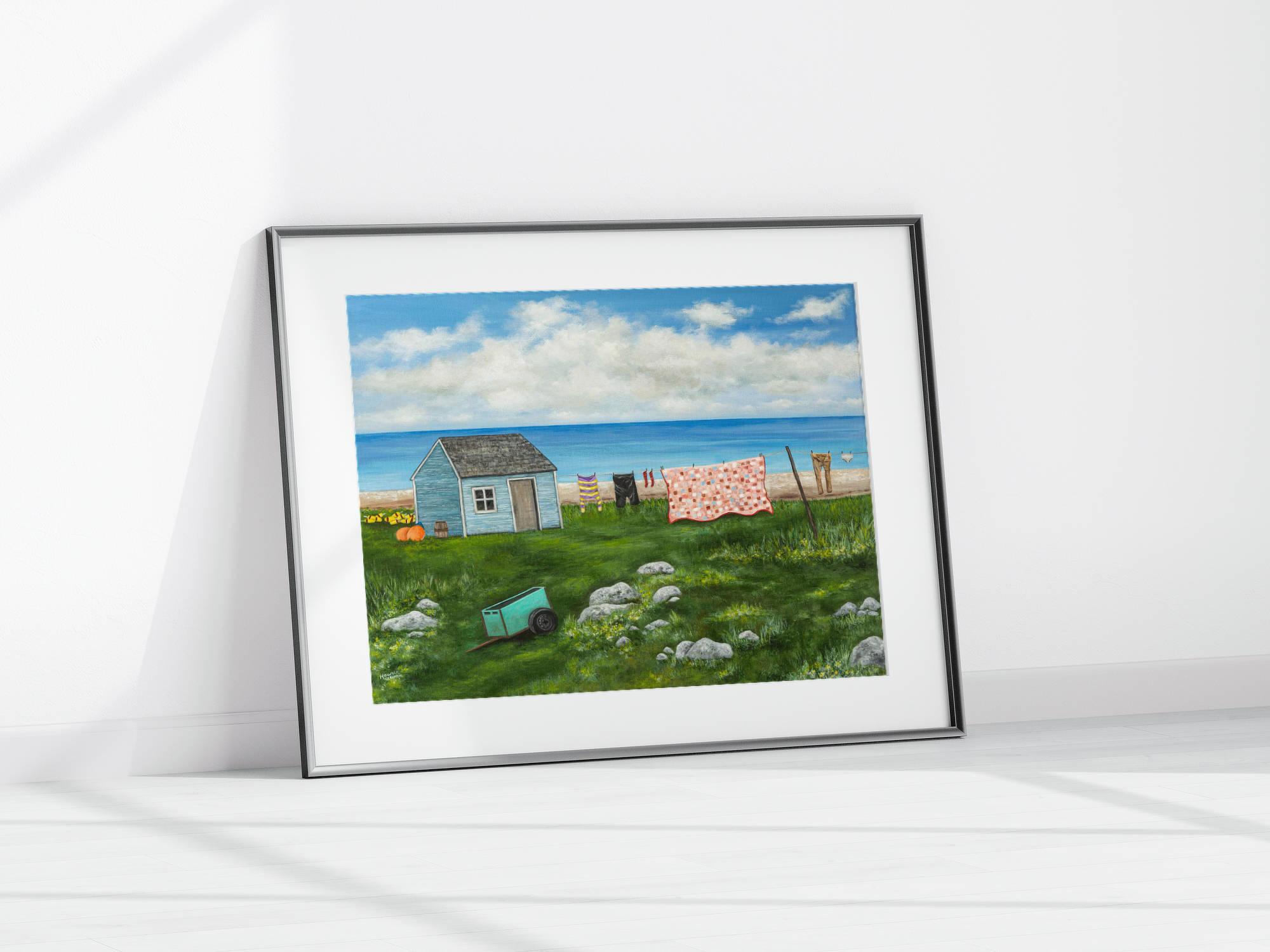 giclee print of seal island nova scotia featuring a shanty, a clothesline with clothes and a quilt and a green cart on a rocky field.