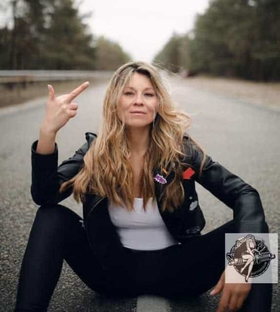 Blonde woman sitting on road with punk rock attitude, outdoor portrait, casual style.