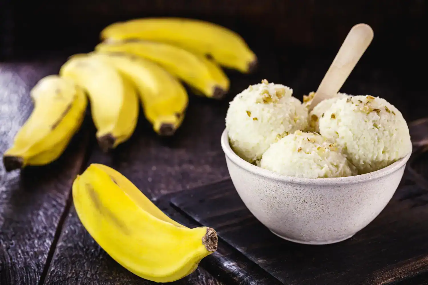 Delicious homemade banana walnut ice cream served in a bowl with fresh bananas nearby.