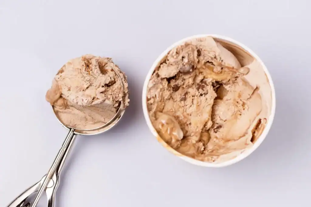 Creamy cashew milk coffee ice cream in a cup and scoop, perfect for coffee lovers.