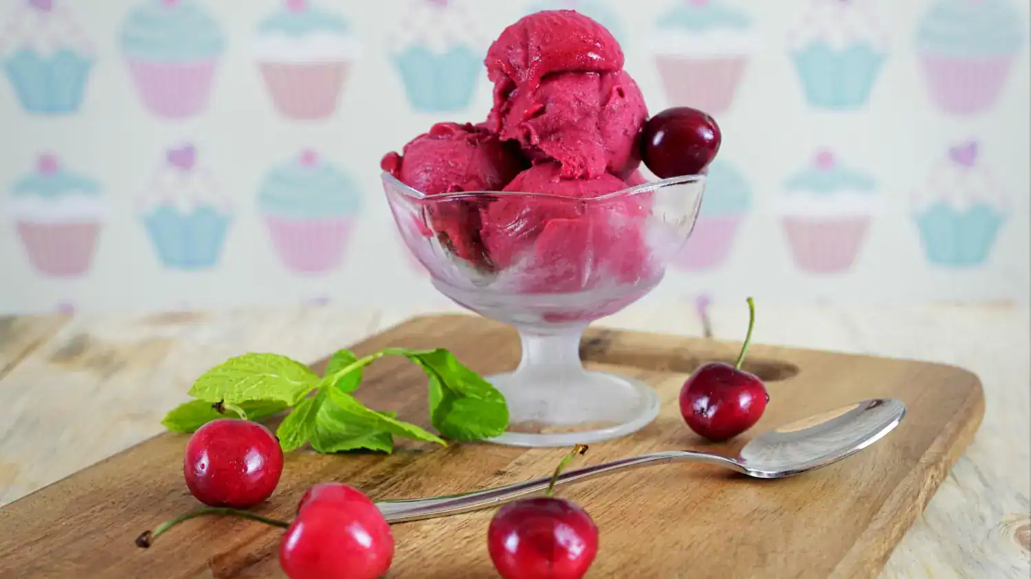 Delicious cherry pie sorbet served in a glass bowl with fresh cherries and mint leaves.