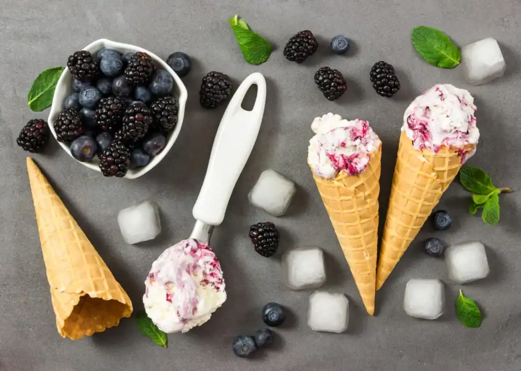Keto Blackberry Cheesecake Ice Cream in waffle cones with fresh berries and mint. Perfect for a low-.