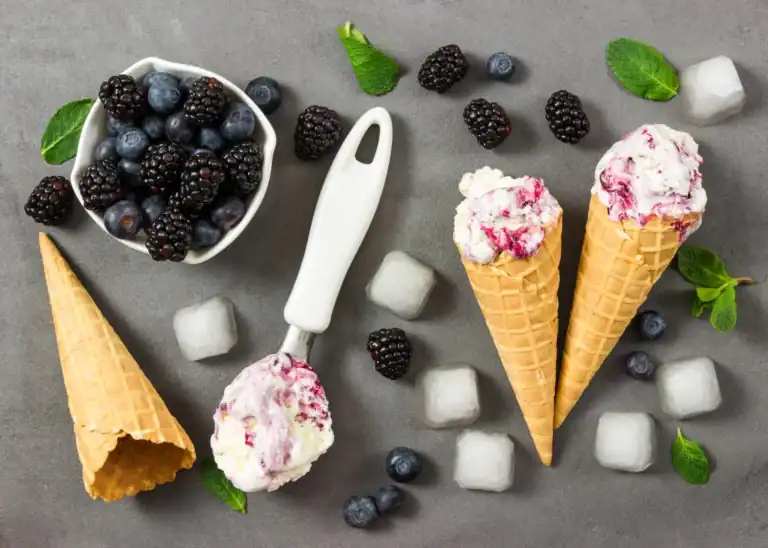 Keto Blackberry Cheesecake Ice Cream in waffle cones with fresh berries and mint. Perfect for a low-.