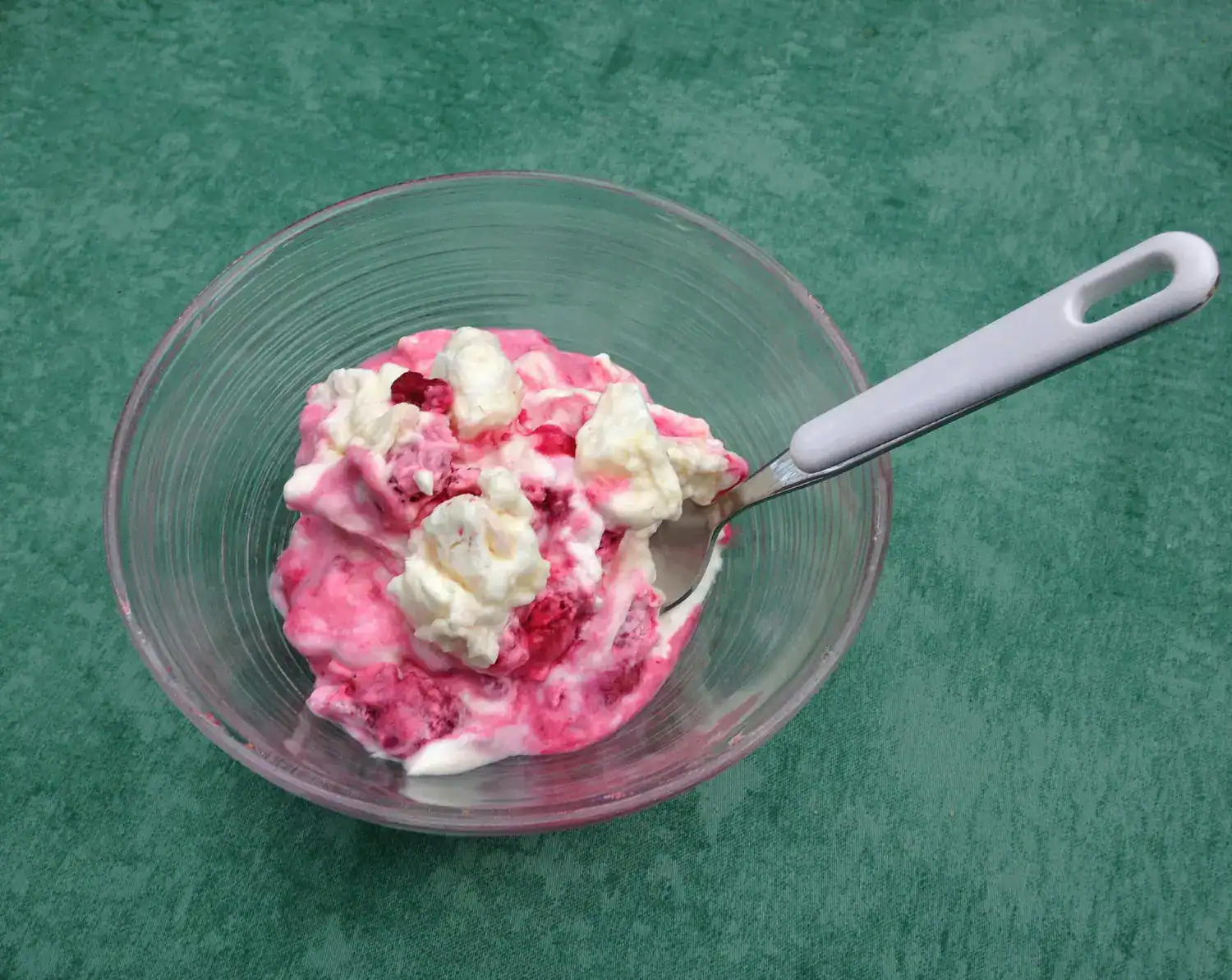 Delicious keto raspberry ripple ice cream in a glass bowl with a spoon.