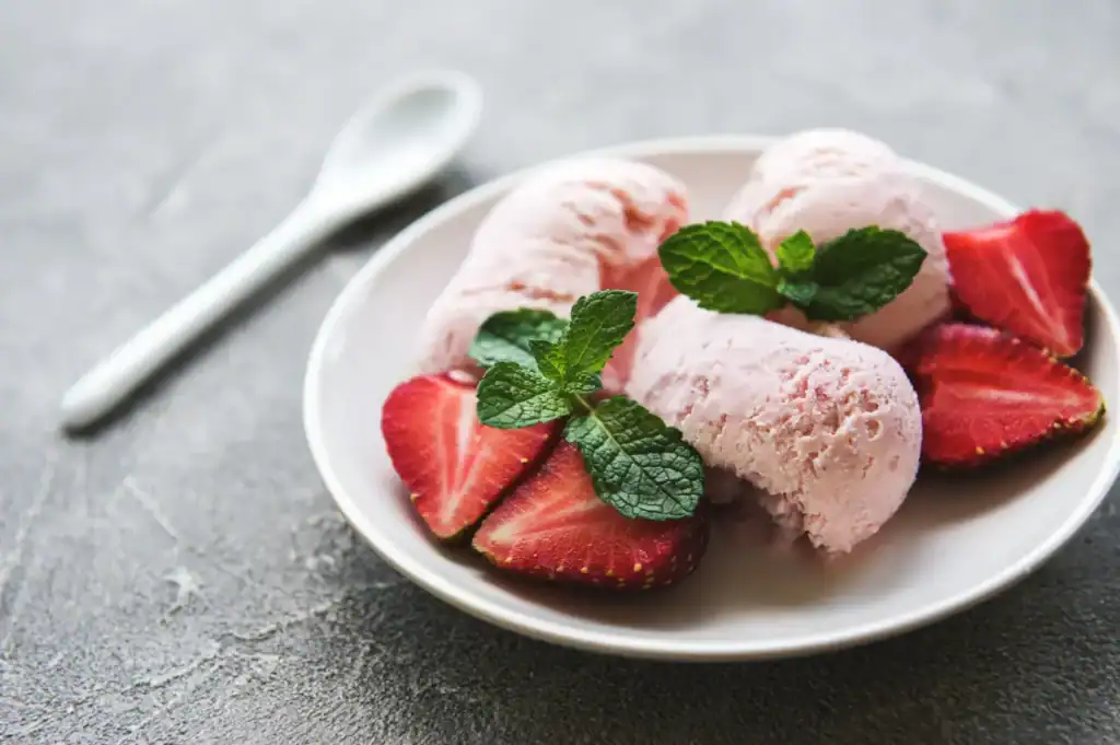 Delicious keto strawberry basil ice cream served with fresh strawberries and mint leaves. Perfect fo.