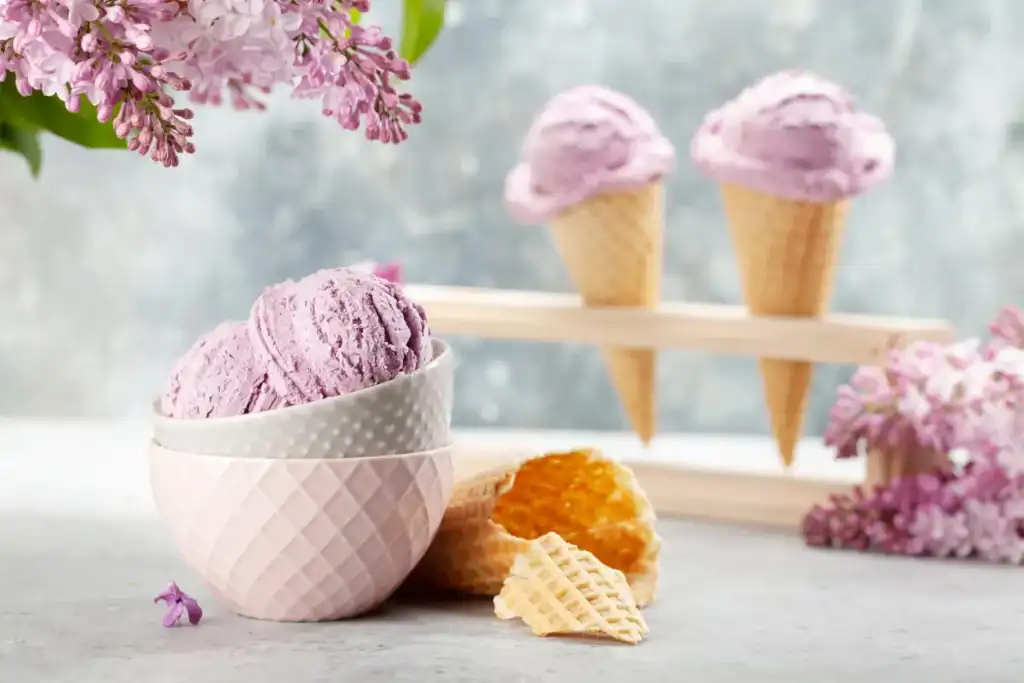 Delicious keto-friendly honey lavender ice cream served in a textured bowl with waffle cone pieces.