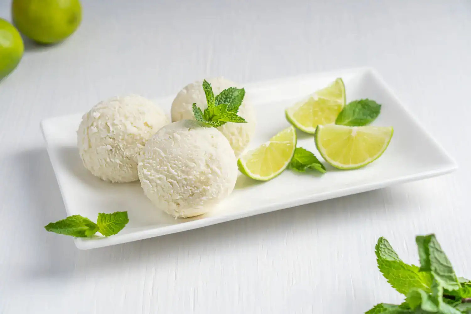 Delicious lime-flavored ice cream balls with fresh lime wedges and mint leaves.