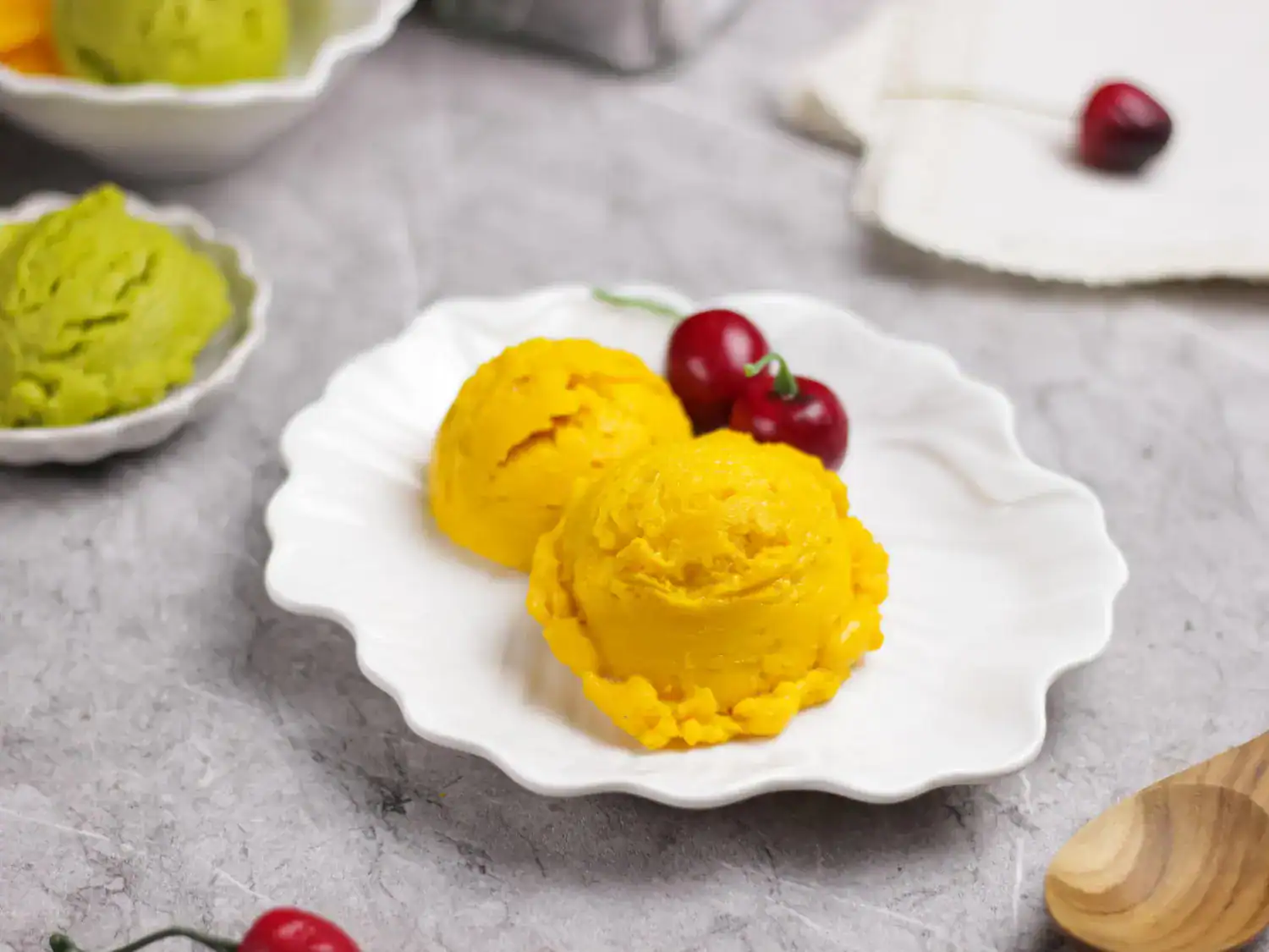 Delicious homemade mango sorbet served on a white plate with cherries, perfect for Ninja Creami reci.