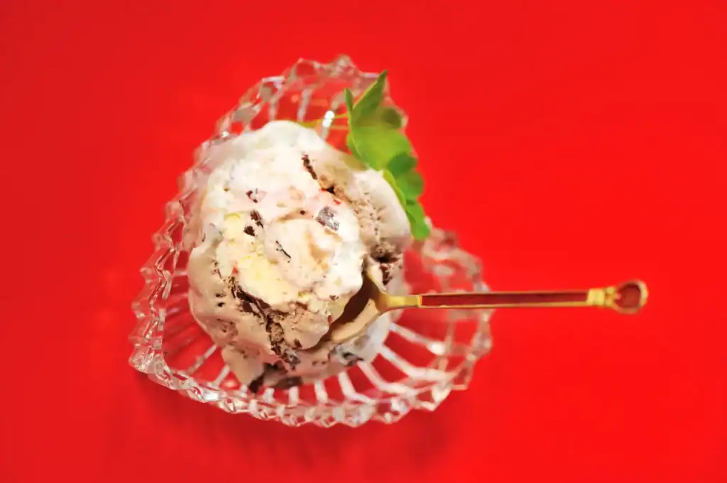 Peppermint Bark Ice Cream with festive toppings on a red background.