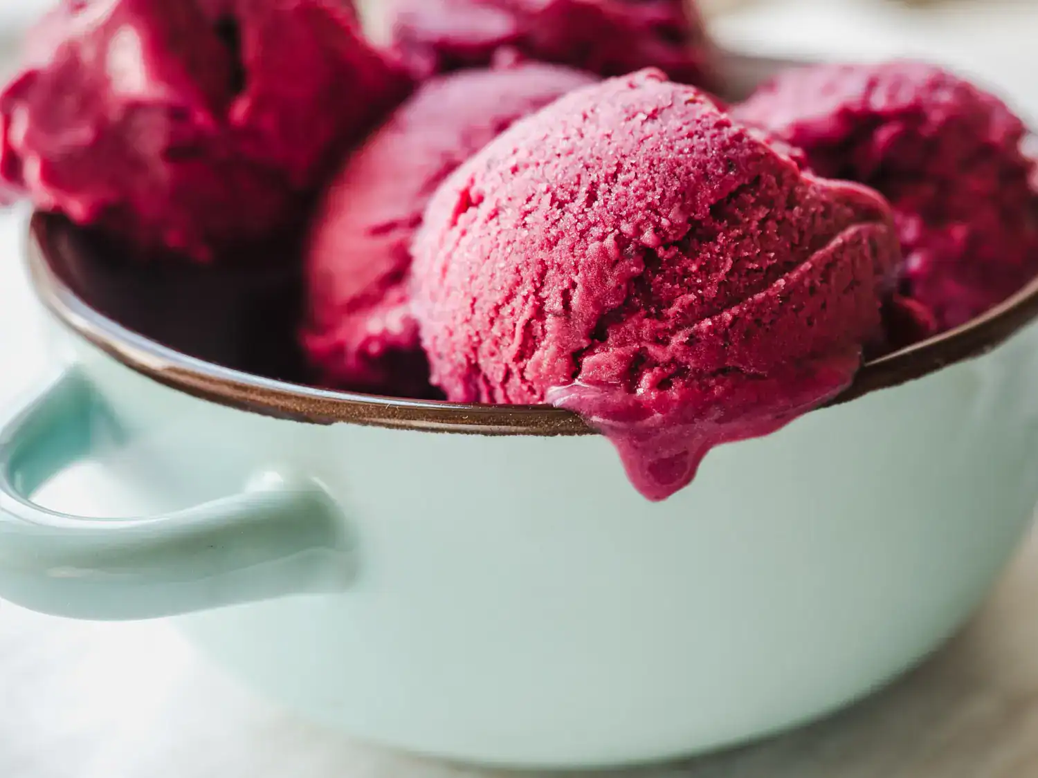 Delicious raspberry rose sorbet served in a light blue bowl, perfect for a refreshing treat.