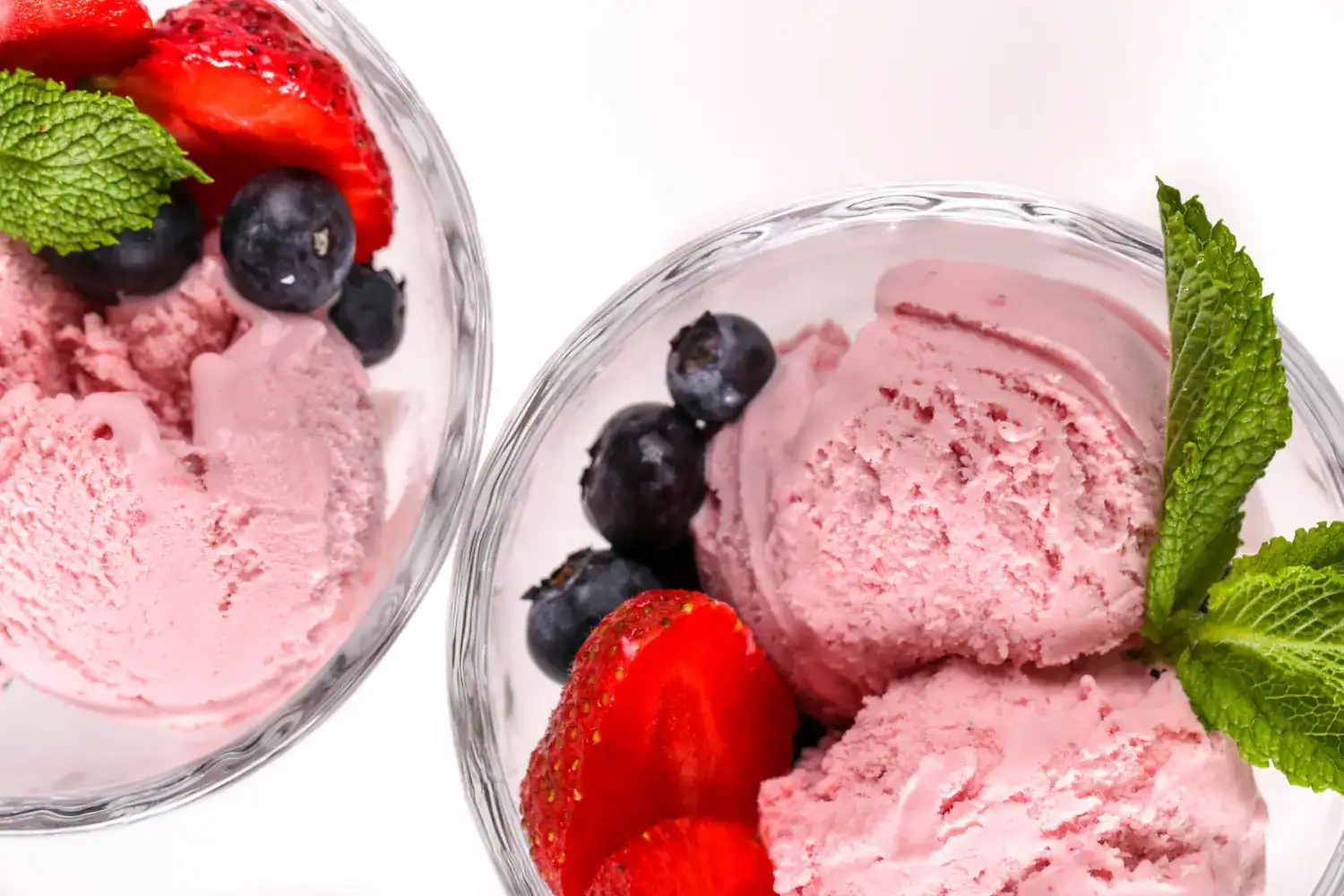 Delicious homemade strawberry ice cream with fresh berries and mint garnish. Perfect for summer trea.