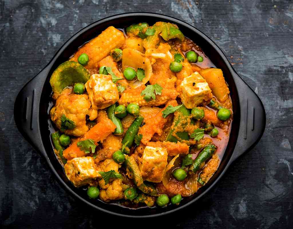 Flavorful Indian vegetable curry with paneer, peas, and spices, served in a black bowl for authentic Indian cuisine.