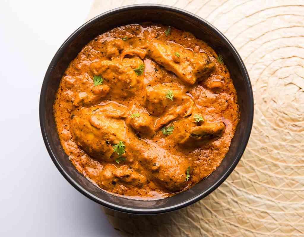 Creamy Indian butter chicken curry served in a black bowl at Crown Indian Cuisine.