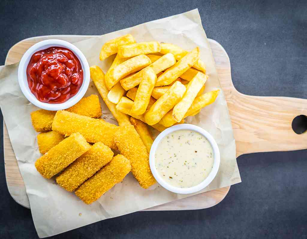 Crunchy fish fillets with fries, ketchup, and tartar sauce - authentic Indian cuisine flavors.