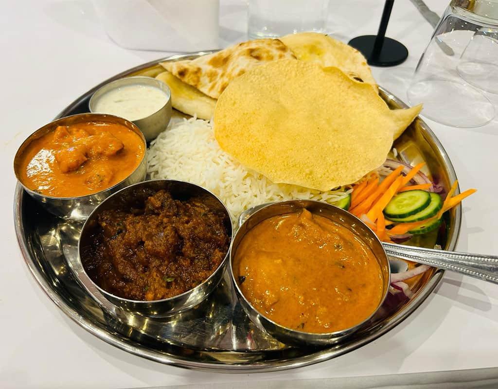 Delicious Indian thali platter with assorted curries, rice, naan, and fresh vegetables. Perfect for traditional Indian cuisine fans.