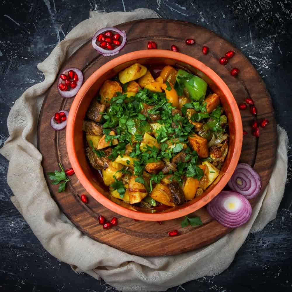 Spicy Indian vegetable curry with potatoes and herbs, served in a rustic bowl.
