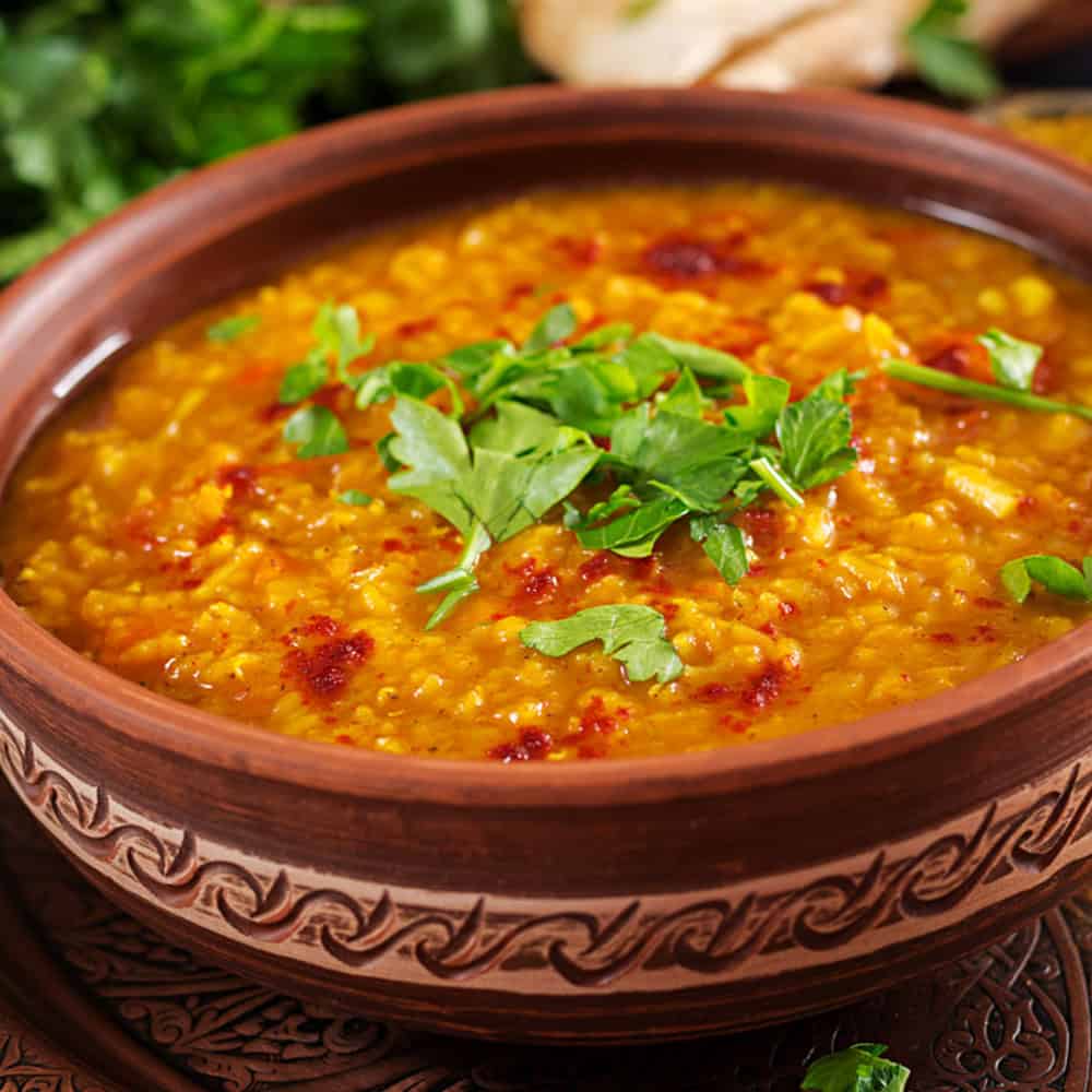 Spicy Indian lentil curry served in a traditional clay bowl with fresh herbs.