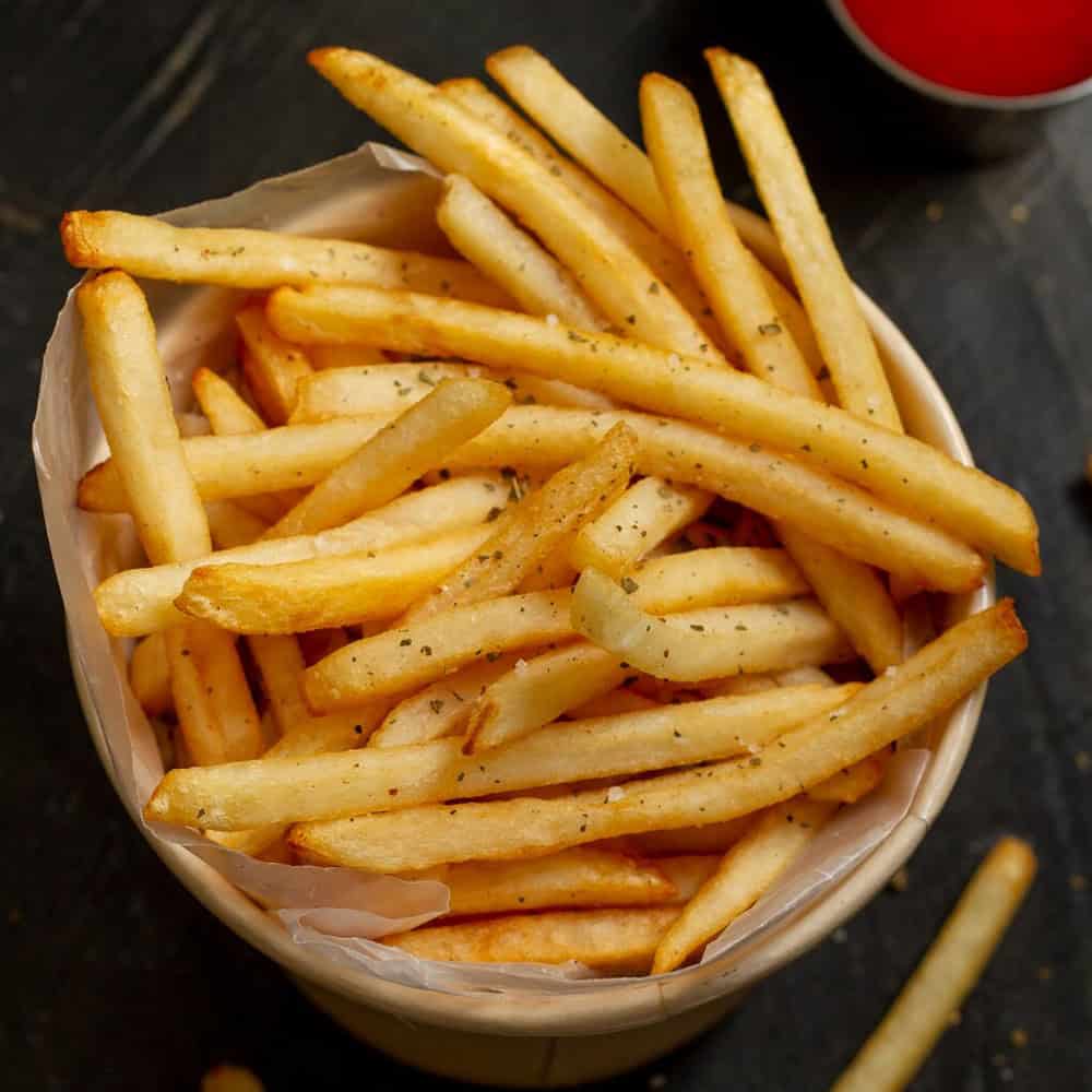 Crispy French fries seasoned with herbs in a basket at Crown Indian Cuisine Windang.