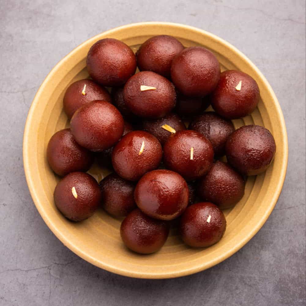 Sweet Indian dessert gulab jamun served in a wooden bowl.