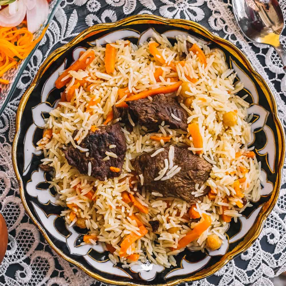 Succulent beef curry with basmati rice, carrots, and chickpeas on a decorative plate.