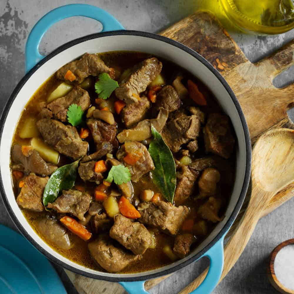 Tender Indian beef curry in a black and white bowl, garnished with cilantro and bay leaves. Located at Crown Indian Cuisine Windang.