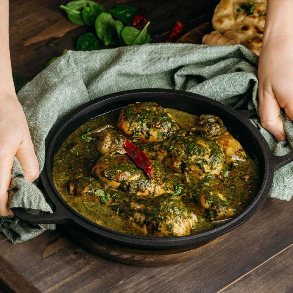 Savory Indian chicken curry with herbs and spices in a black skillet.