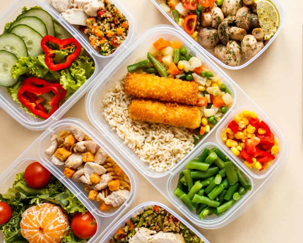 Fresh Indian cuisine takeaway boxes with vibrant salads, curries, and rice from Crown Indian Windang.