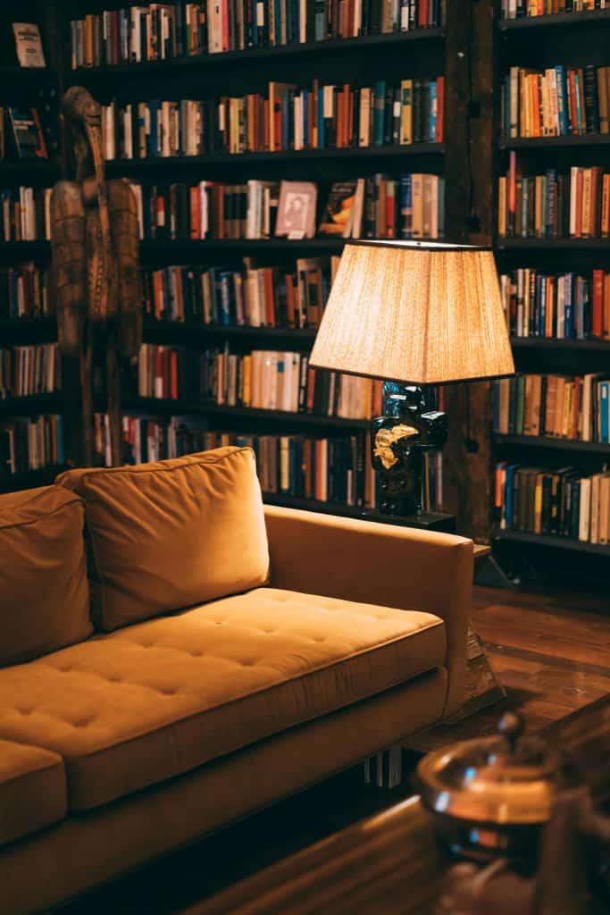 pexels-photo-1907784-1907784 Warm and inviting library scene featuring a cozy couch, bookshelves, and a lamp for ambient lighting.