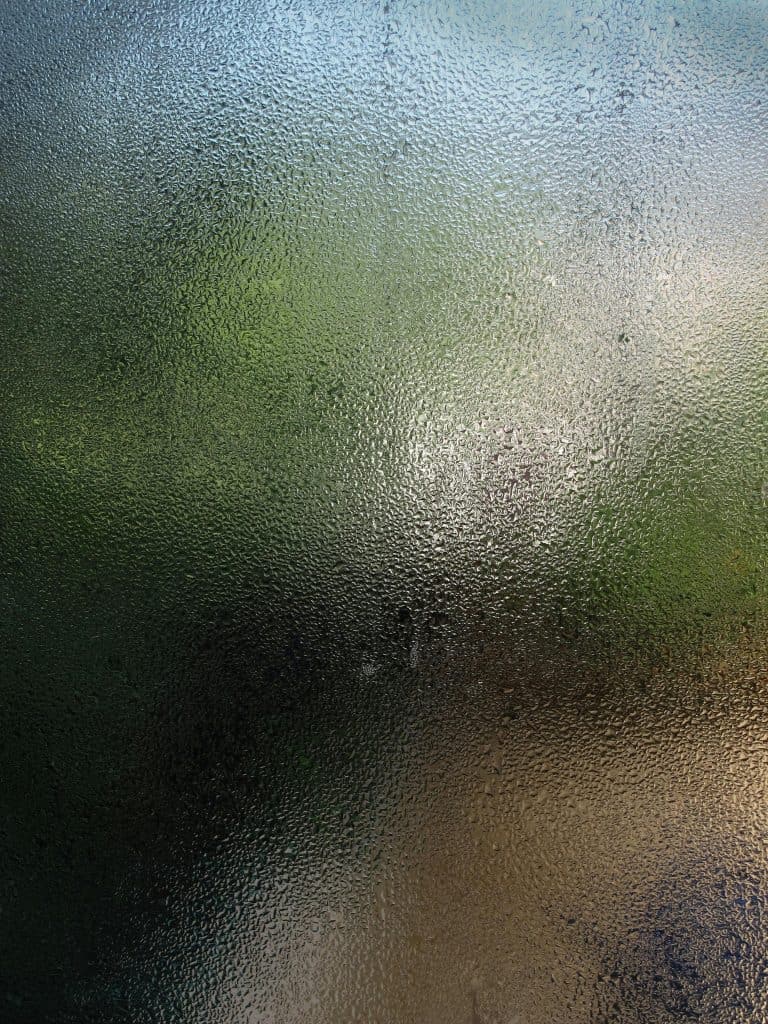 pexels-photo-459277-459277 Close-up view of a wet glass pane with water droplets creating a blurred background effect.