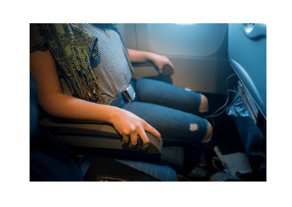 Passenger seated comfortably on airplane with armrest and seatbelt.