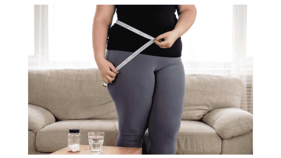 Woman measuring her waist with a tape measure for weight loss.