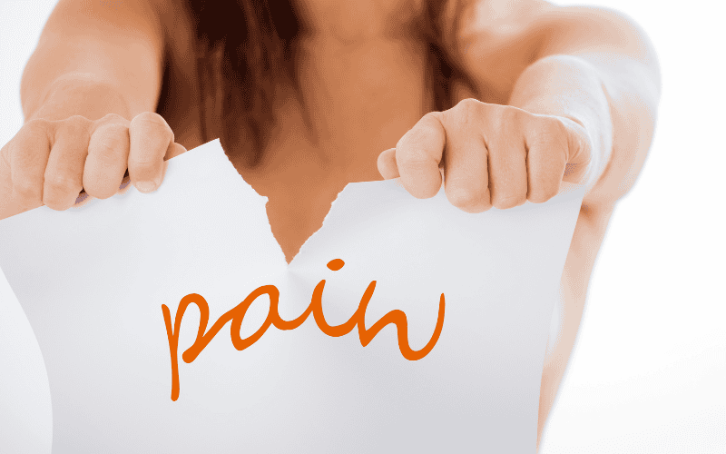 Person tearing paper with 'pain' written on it, symbolising pain relief.