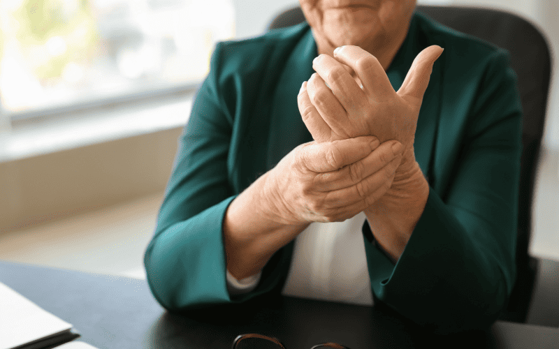 Elderly woman experiencing wrist pain during hypnotherapy session.