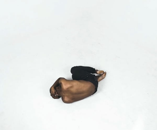 Person lying on the floor in a curled position for pain relief or therapy.