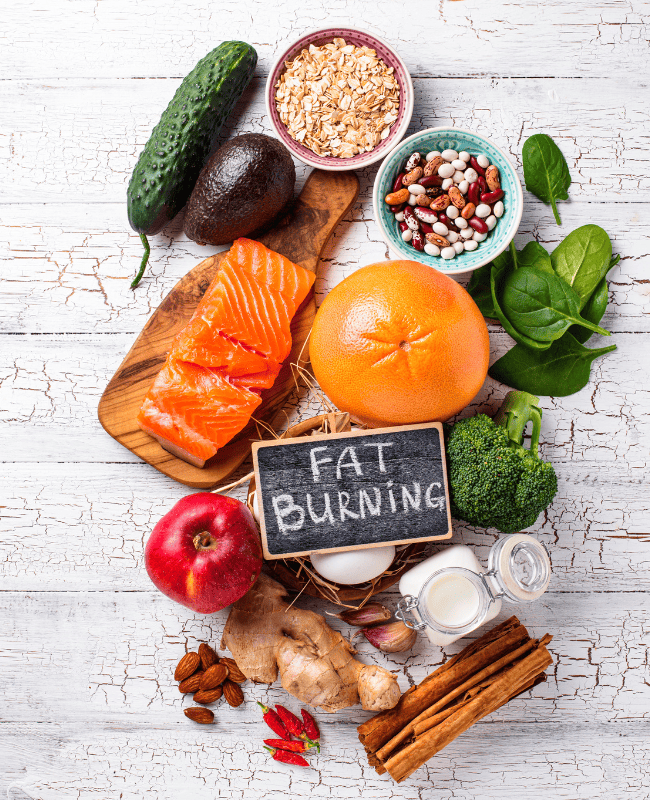 Healthy foods including salmon, avocado, apple, and vegetables for fat burning.