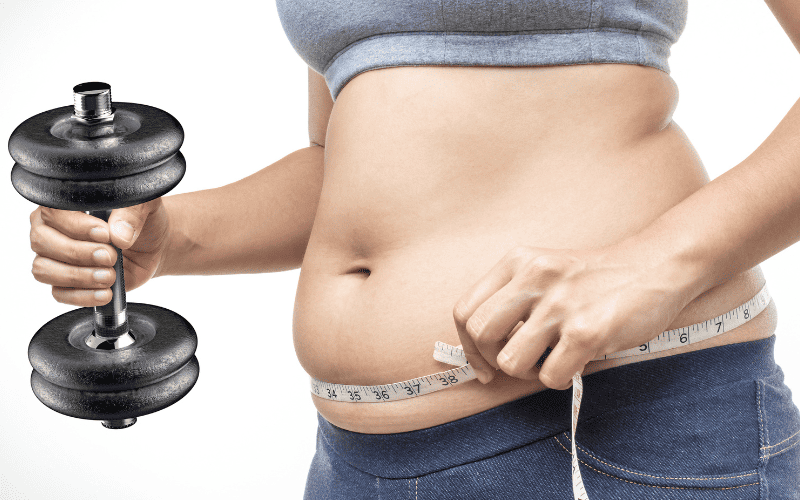 Person measuring waist with tape and holding dumbbell for fitness.