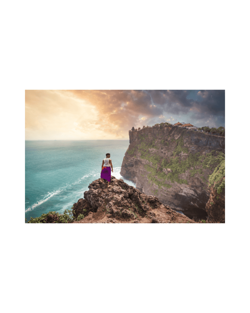 A person standing on a high cliff, looking out over the sea with confidence and ease.