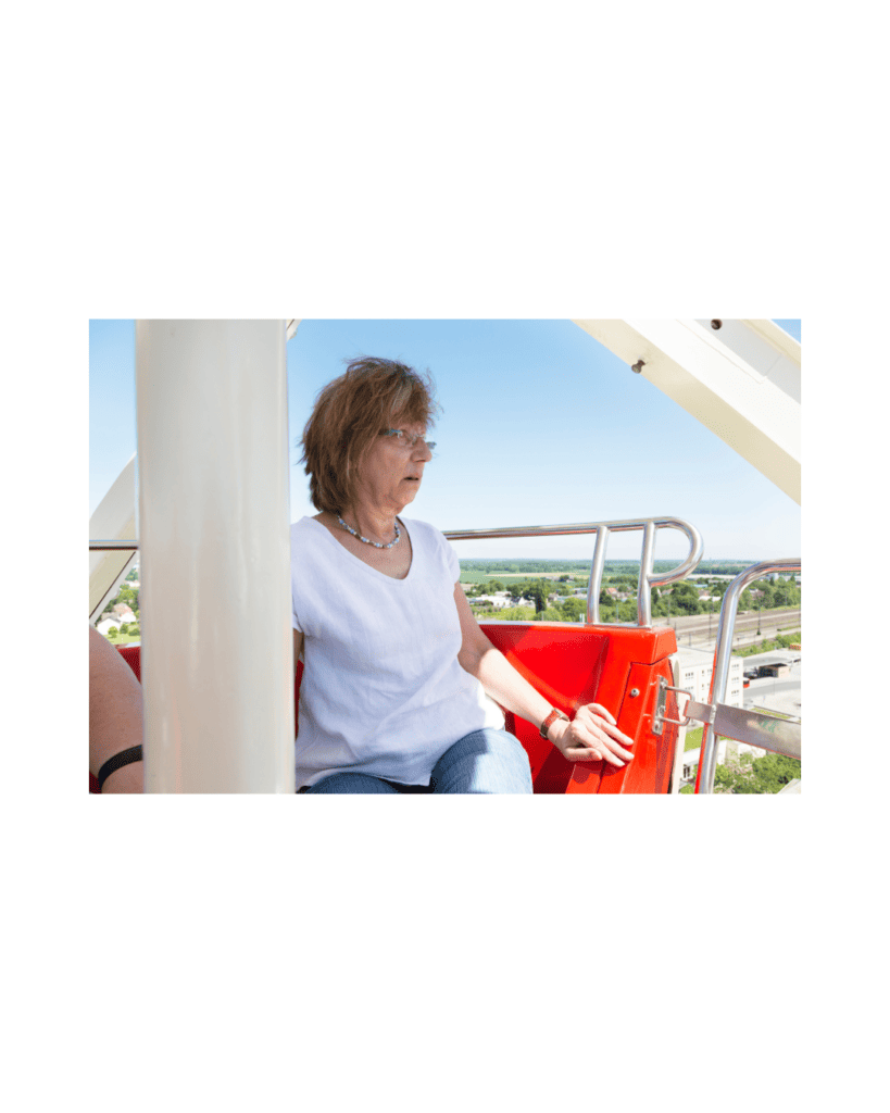 A woman gripping the seat of a Ferris wheel, looking anxious as she faces her fear of heights.