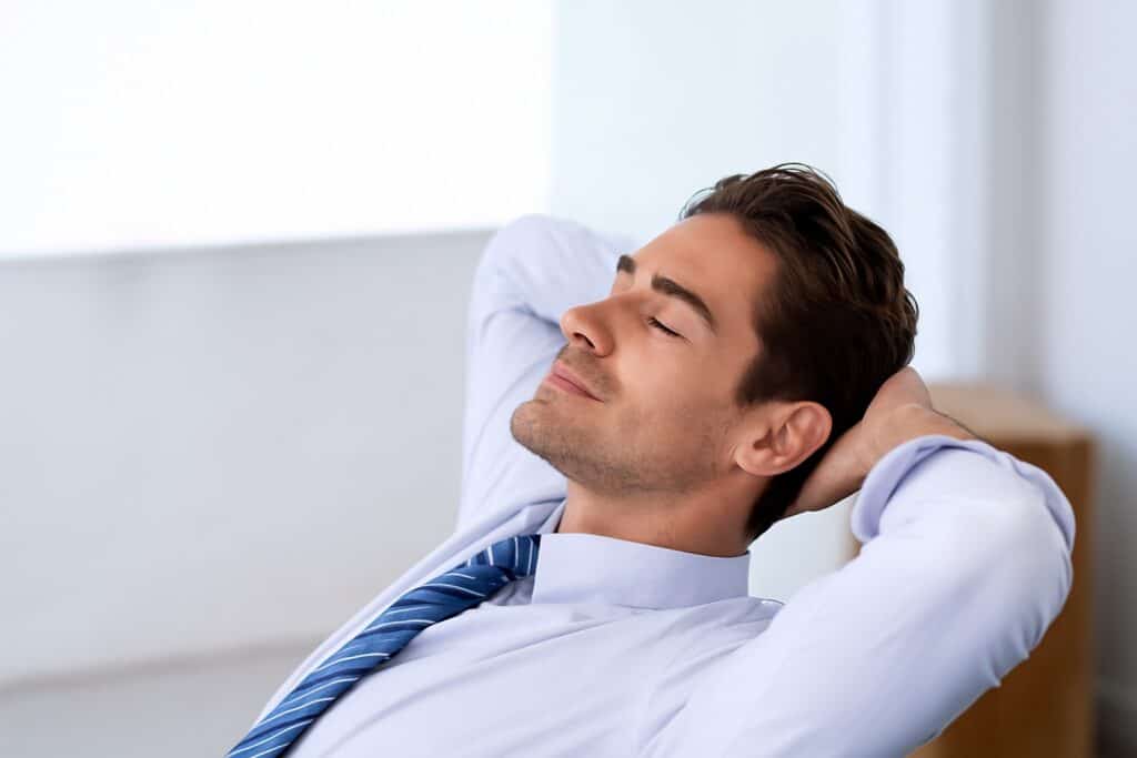 Man in shirt and tie leaning back with eyes closed, looking calm, relaxed, and content.
