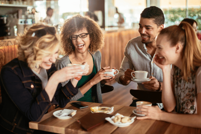 Group of young adults laughing and bonding over coffee in a café.