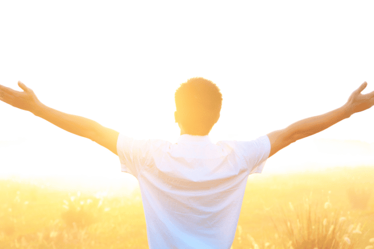Man standing in sunlight with arms outstretched, symbolising freedom and clarity