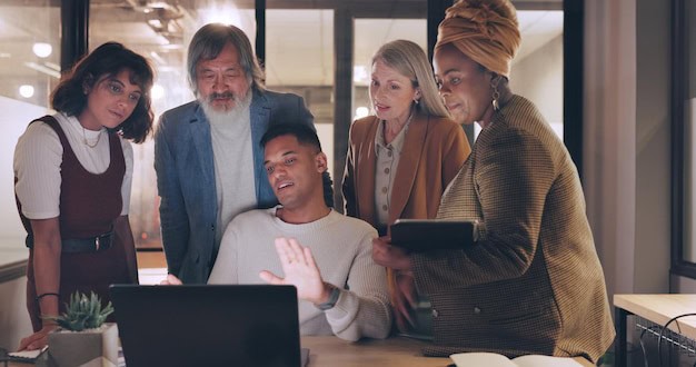 Diverse group of professionals gathered around a laptop, collaborating in a calm and supportive work environment.