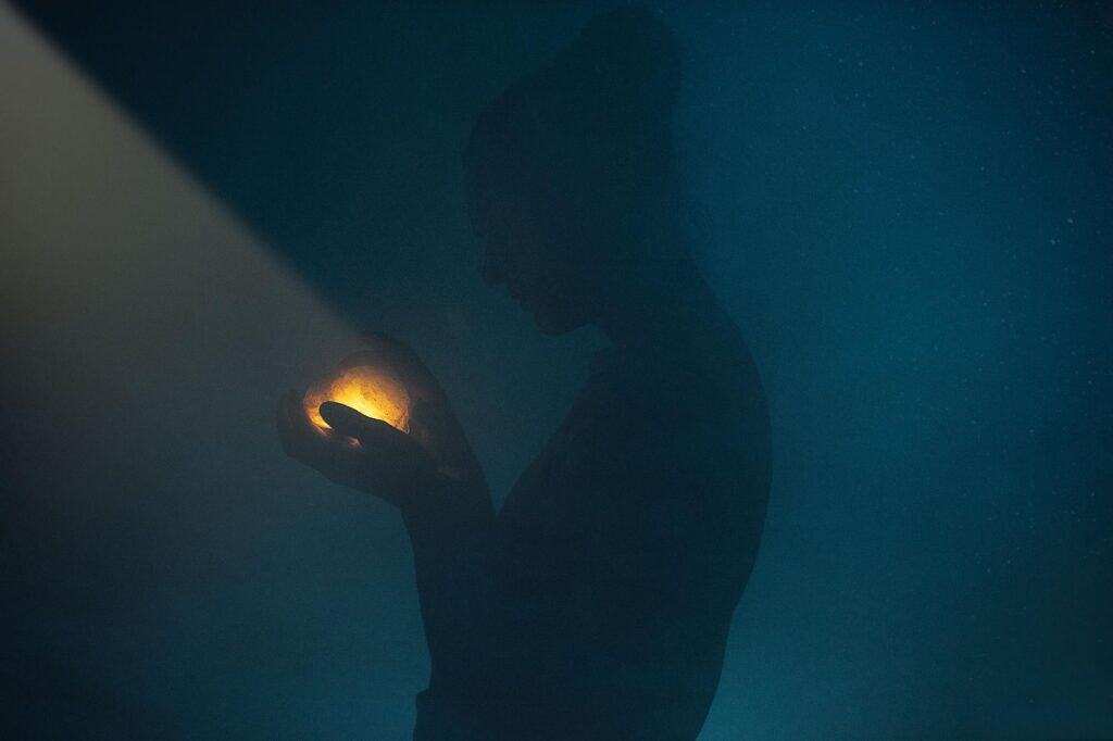 Silhouette of a woman holding a glowing orb in the dark, symbolizing inner strength and transformation