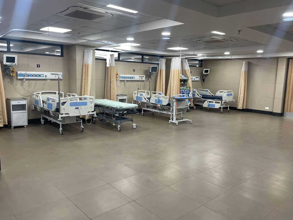 Empty hospital ICU ward with patient beds and medical equipment for cardiac care.
