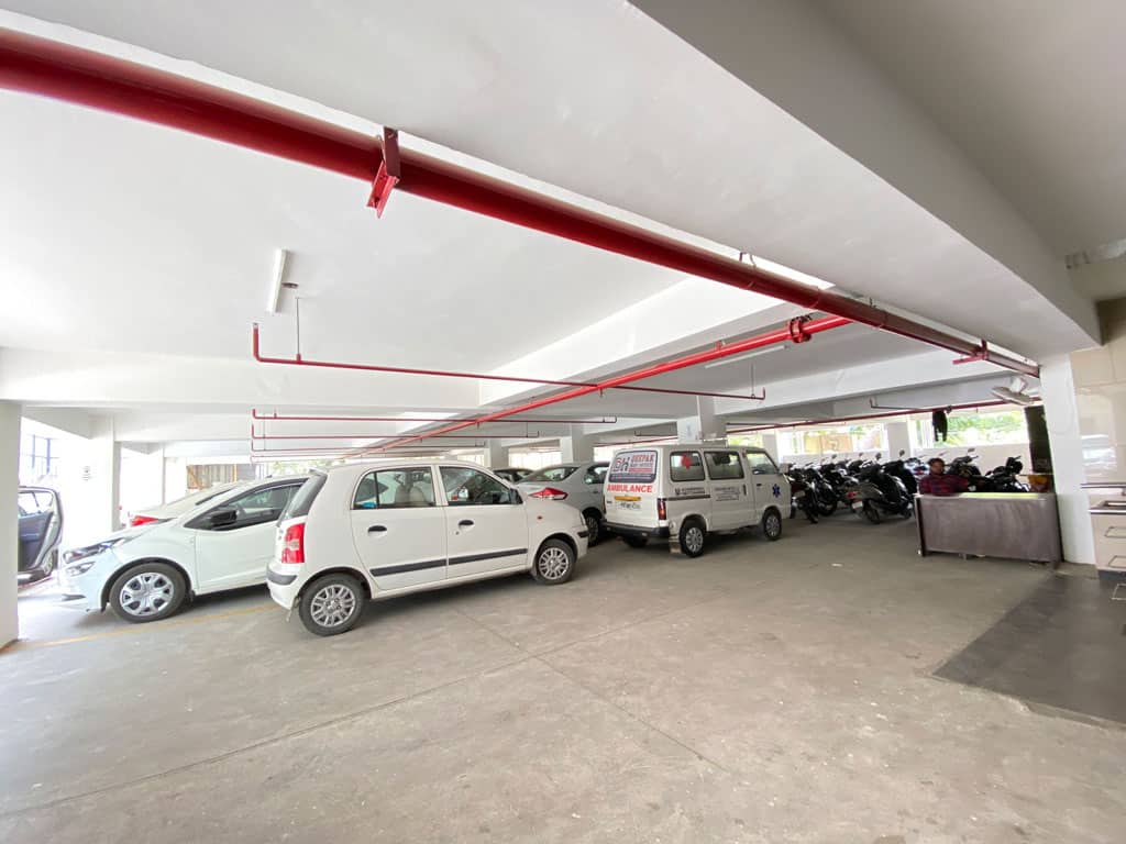 Parking garage at Deepak Heart Institute with cars and motorcycles.